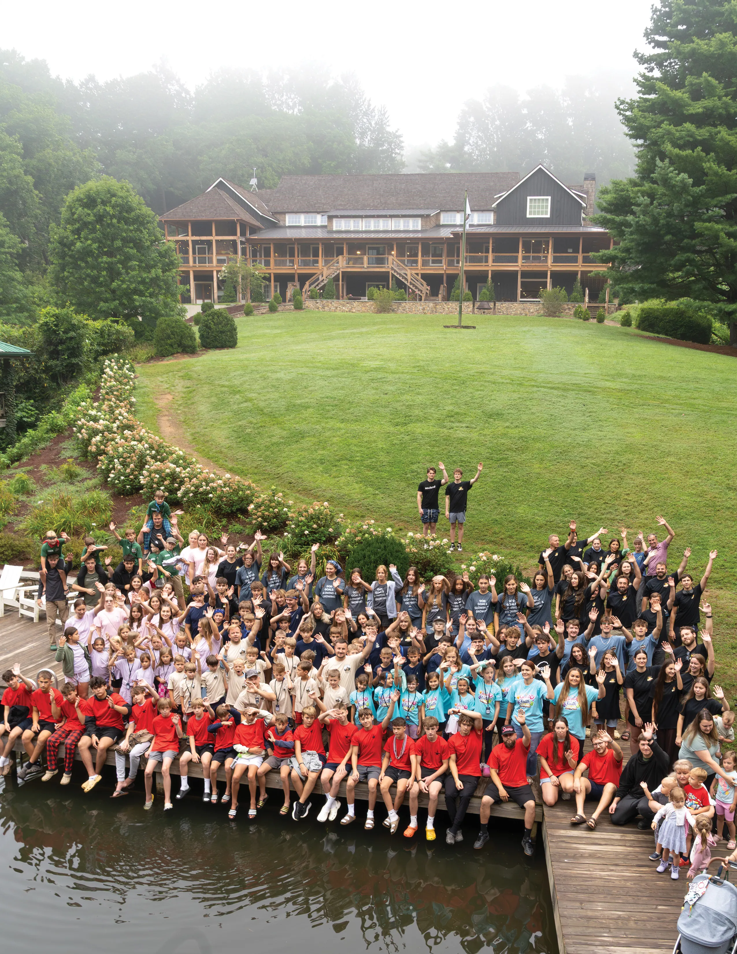 The whole camp waves from the dock and the lawn in front of the lodge.