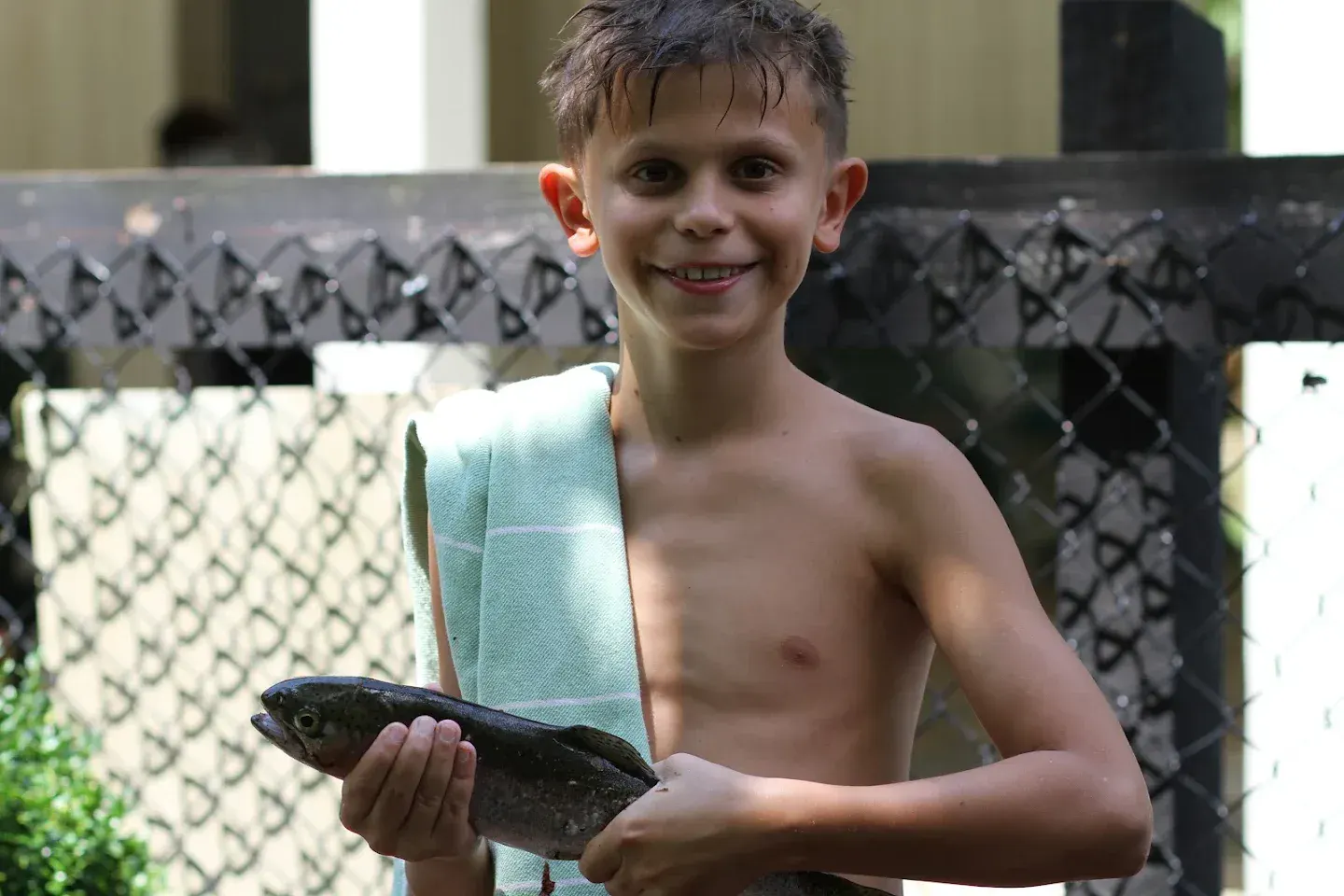 A smiling camper proudly holds up the fish he caught.