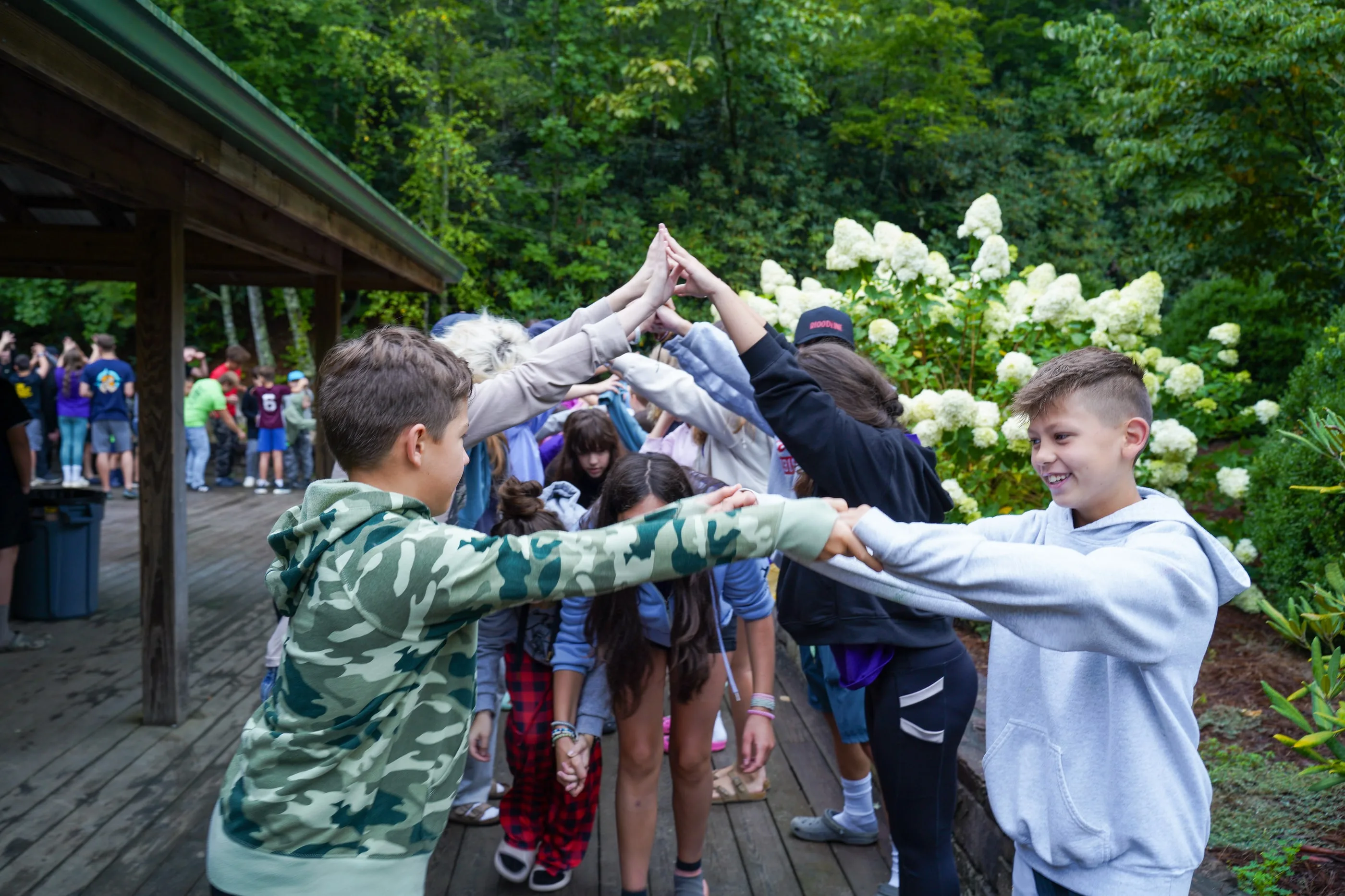Campers form an arch with their hands and high-five a line of children running through it.
